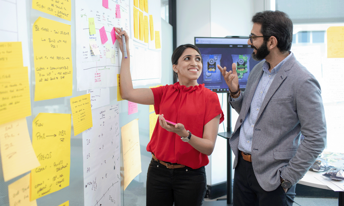 Two employees adding sticky notes to a wall